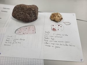 Deux échantillons de roches posés sur une feuille où des élèves ont réalisé des dessins et noté leurs observations sur la texture, la densité et la couleur.