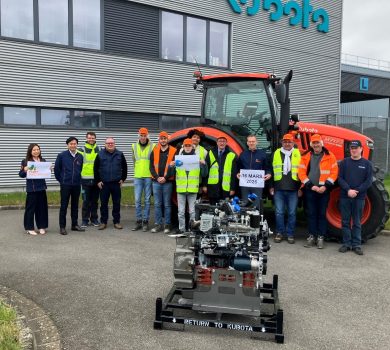 Groupe d’élèves et de professionnels posant devant un tracteur Kubota et un moteur industriel lors d’une opération de don sur le site de l’entreprise.