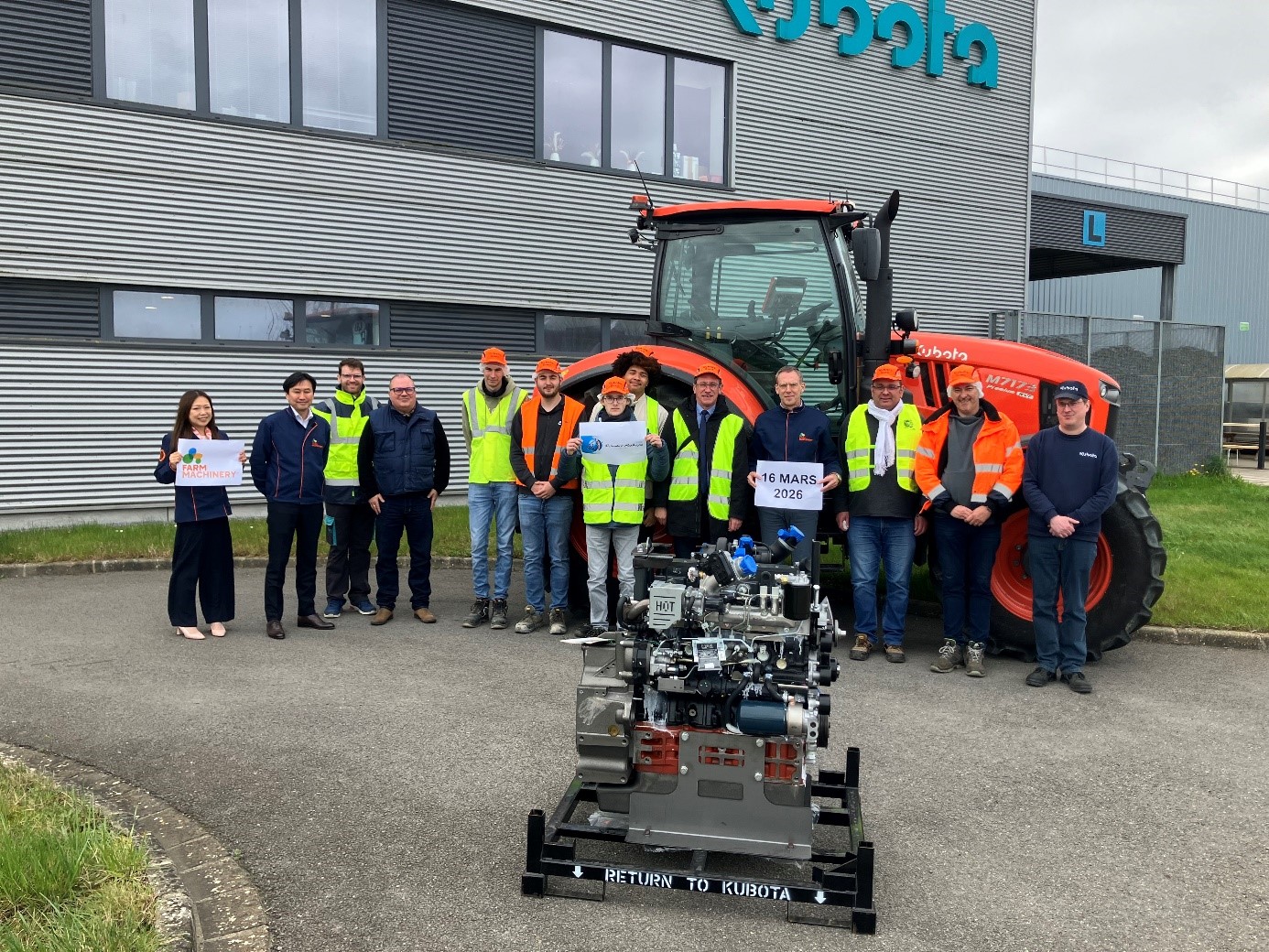 Groupe d’élèves et de professionnels posant devant un tracteur Kubota et un moteur industriel lors d’une opération de don sur le site de l’entreprise.