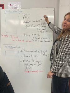 Une enseignante expliquant au tableau les éléments de conception d’une couverture de livre aux élèves dans le cadre du projet Jeunes en librairie.