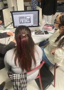 Élèves de 3PPM et 2MIGC travaillant ensemble sur ordinateur pour concevoir une jaquette de livre lors d’un atelier en industries graphiques.