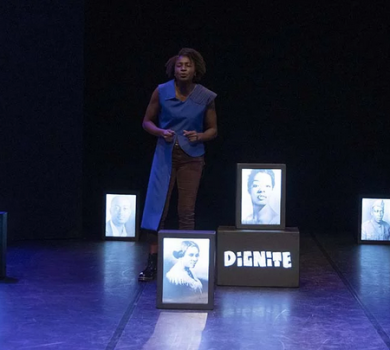 Comédienne seule sur scène entourée de portraits lumineux lors du spectacle « J’ai plusieurs terres », évoquant mémoire, identité et héritage