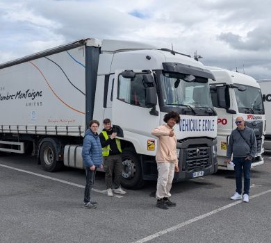 Des élèves et un formateur devant des camions.