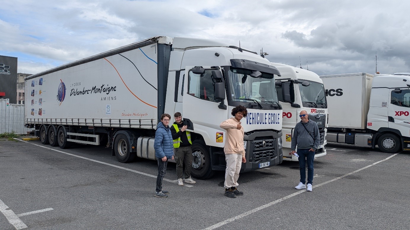 Des élèves et un formateur devant des camions.