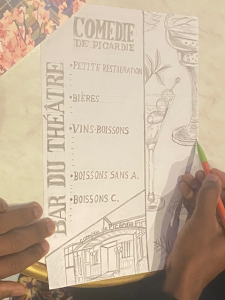 Un élève dessine une proposition de carte pour le bar de la Comédie de Picardie, inspirée de l’univers du théâtre.